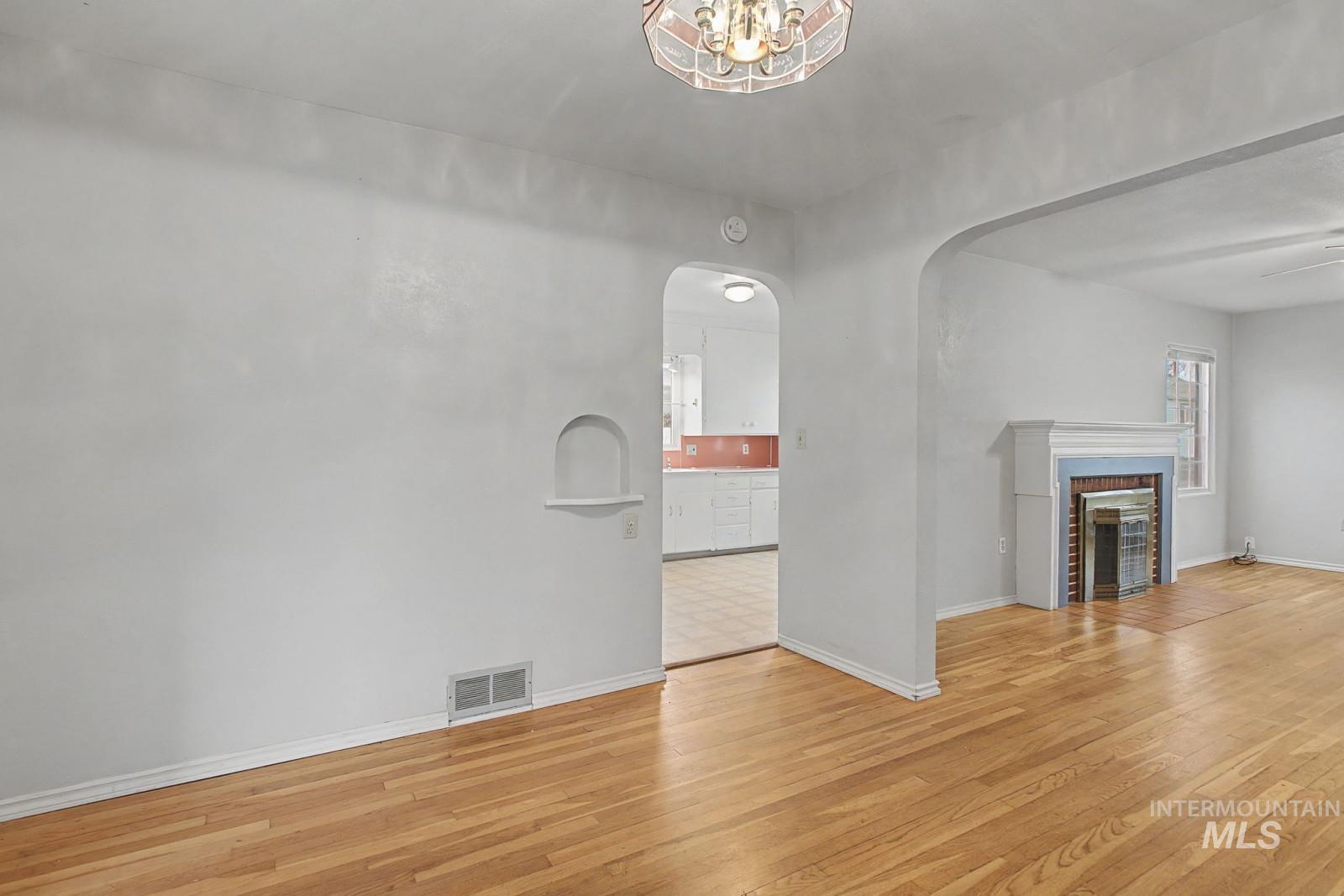 918 Elm Street Clarkston, WA 99403 - Photo 9 of 35 Unfurnished living room featuring light wood-style floors, a brick fireplace, arched walkways, and a ceiling fan