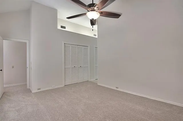 an empty room with a chandelier fan and a ceiling fan