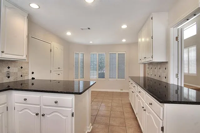 a kitchen with granite countertop white cabinets and white appliances