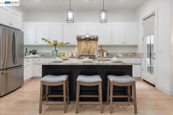 a kitchen with stainless steel appliances granite countertop a table chairs stove and refrigerator