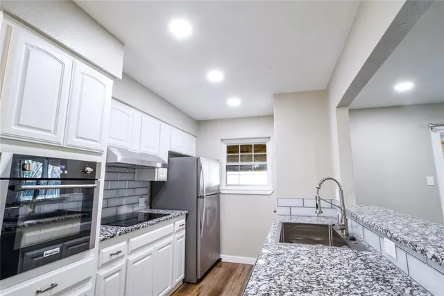 a kitchen with stainless steel appliances kitchen island granite countertop a refrigerator and a stove top oven