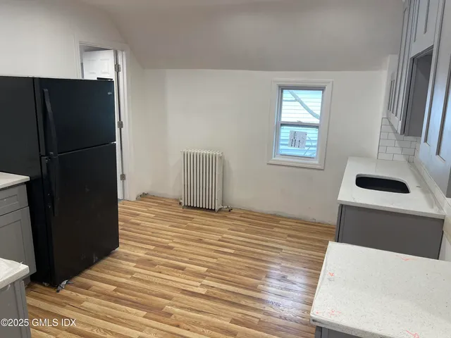 a view of kitchen and empty room with wooden floor