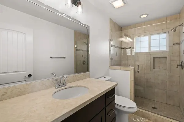 a bathroom with a granite countertop sink a toilet a mirror and shower