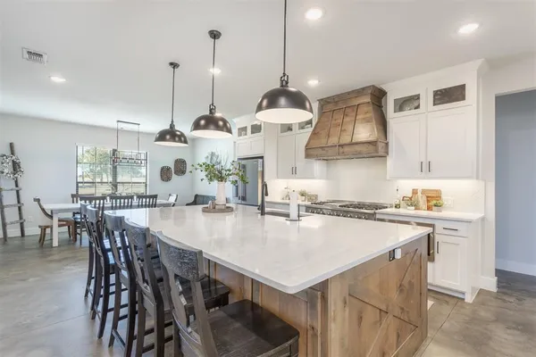 a kitchen with stainless steel appliances kitchen island a table chairs and a refrigerator