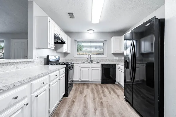 a kitchen with white cabinets sink and stainless steel appliances