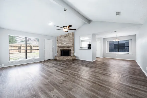 a view of an empty room with wooden floor fireplace and a window