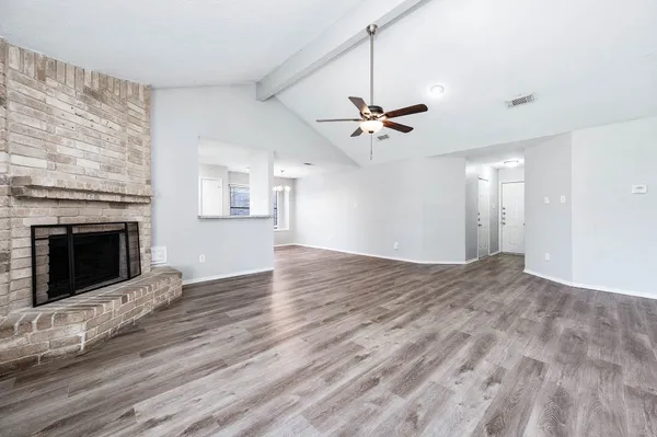 a view of an empty room with wooden floor fireplace and a window