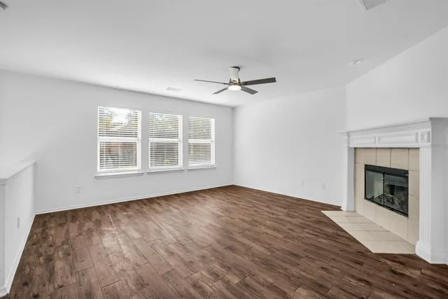 a view of an empty room with wooden floor fireplace and a window