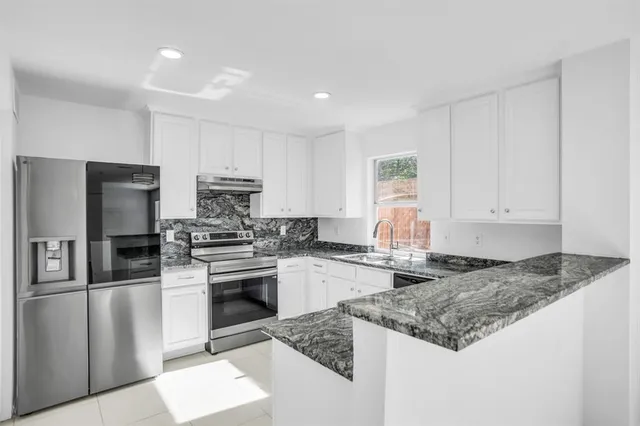 a kitchen with granite countertop white cabinets white appliances and a sink