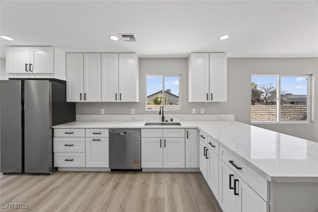 7071 Wedgewood Way Las Vegas, NV 89147 - Photo 10 of 37 Kitchen with stainless steel appliances, white cabinetry, light stone countertops, light wood finished floors, and recessed lighting