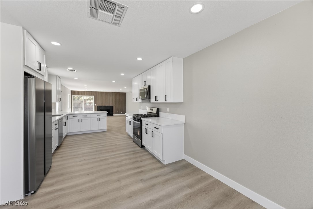 7071 Wedgewood Way Las Vegas, NV 89147 - Photo 11 of 37 Kitchen featuring stainless steel appliances, white cabinets, a peninsula, light wood-style floors, and recessed lighting