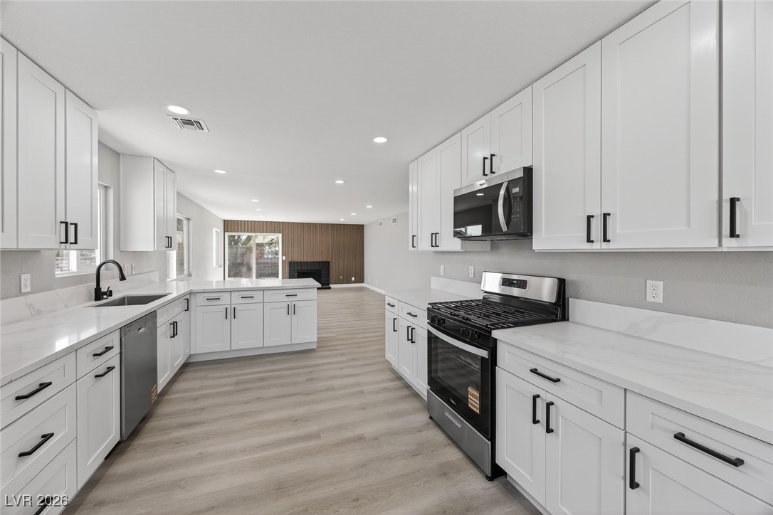 7071 Wedgewood Way Las Vegas, NV 89147 - Photo 13 of 37 Kitchen with stainless steel appliances, white cabinetry, light stone countertops, light wood finished floors, and recessed lighting