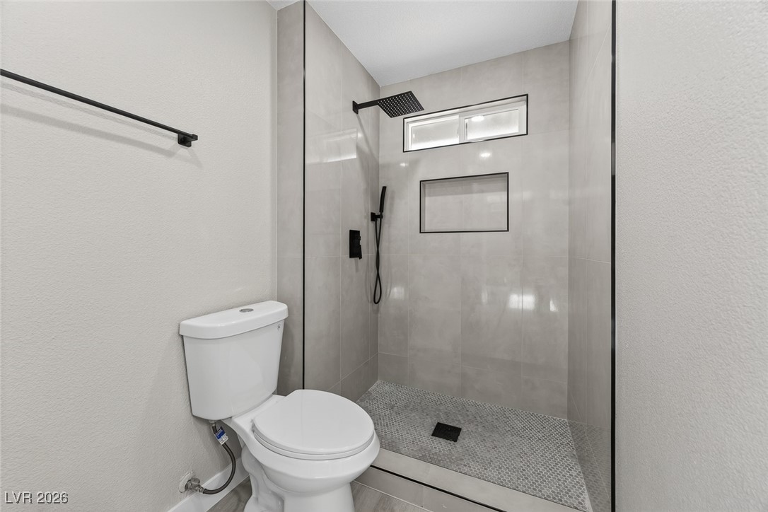 7071 Wedgewood Way Las Vegas, NV 89147 - Photo 23 of 37 Full bathroom featuring a tile shower and a textured wall