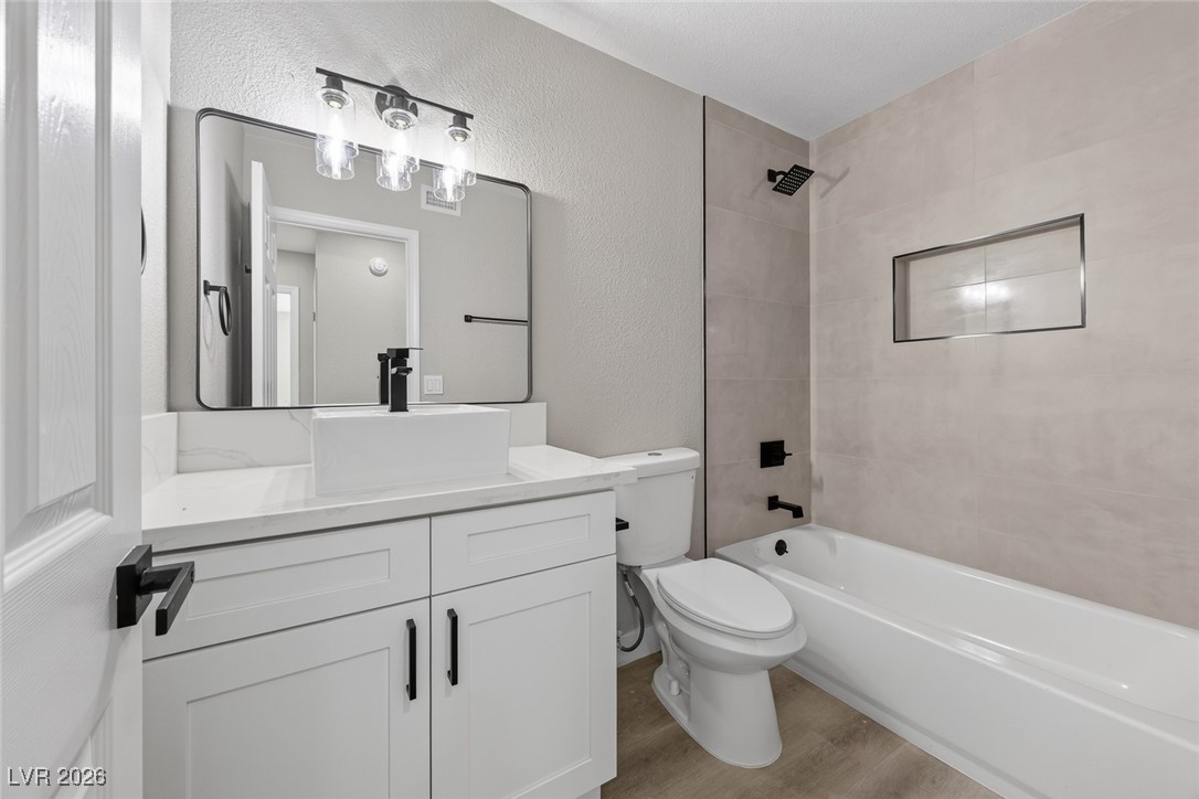7071 Wedgewood Way Las Vegas, NV 89147 - Photo 26 of 37 Full bathroom with a textured wall, shower / bath combination, vanity, and light wood-type flooring