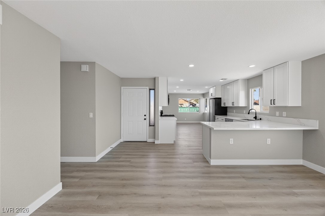 7071 Wedgewood Way Las Vegas, NV 89147 - Photo 5 of 37 Kitchen featuring white cabinets, light wood finished floors, a peninsula, recessed lighting, and light stone countertops