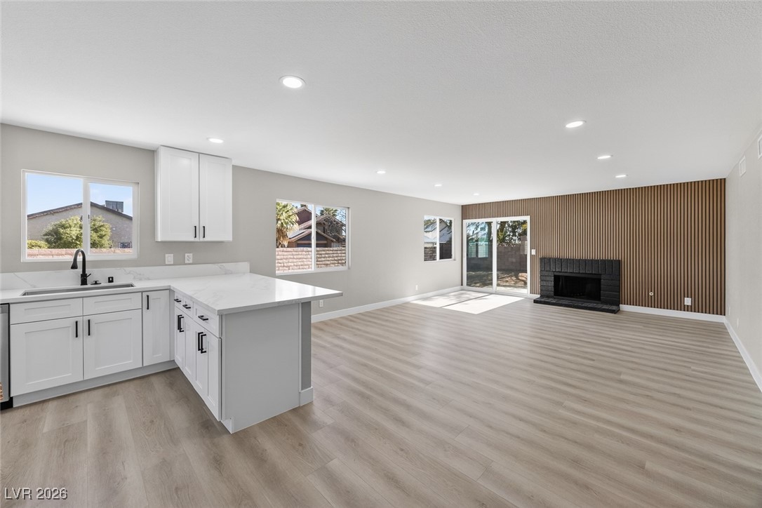 7071 Wedgewood Way Las Vegas, NV 89147 - Photo 37 of 37 Kitchen featuring wooden walls, white cabinetry, a peninsula, open floor plan, and light wood-type flooring