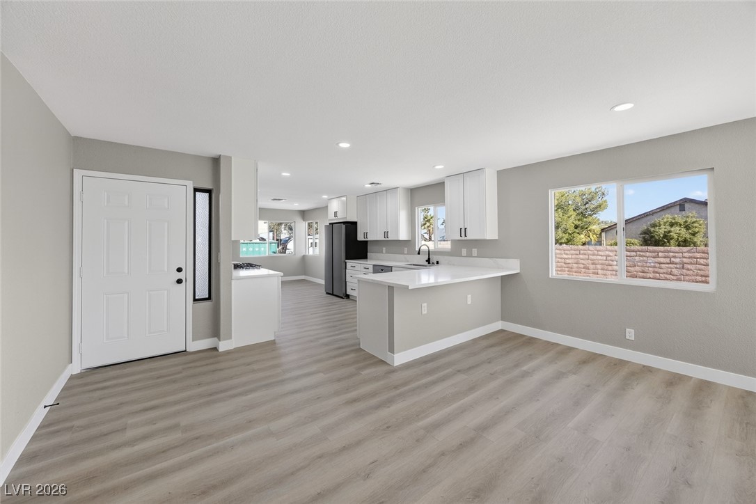 7071 Wedgewood Way Las Vegas, NV 89147 - Photo 6 of 37 Kitchen with white cabinets, a peninsula, freestanding refrigerator, light wood finished floors, and recessed lighting