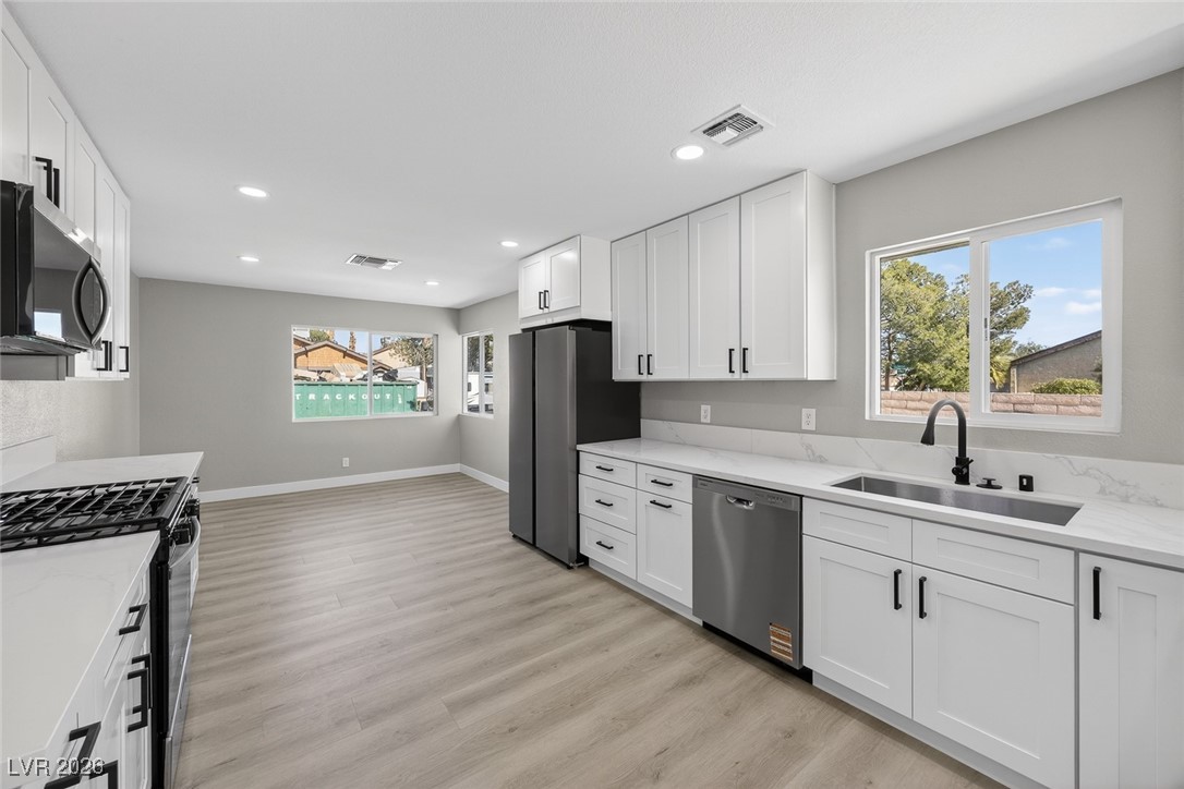 7071 Wedgewood Way Las Vegas, NV 89147 - Photo 9 of 37 Kitchen featuring stainless steel appliances, white cabinetry, light wood-style flooring, light stone counters, and recessed lighting