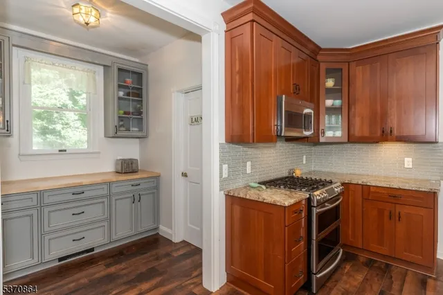 a kitchen with stainless steel appliances granite countertop a sink a stove cabinets and wooden floor