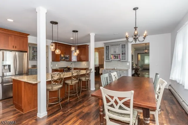a dining room with stainless steel appliances kitchen island granite countertop a table chairs and a refrigerator