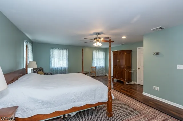 a bedroom with a bed lamp on desk and a window