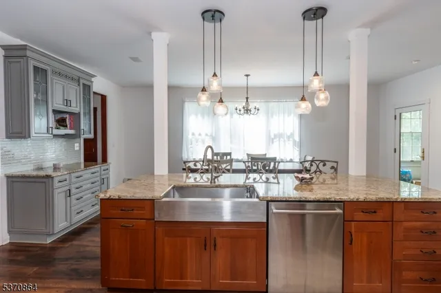 a kitchen with kitchen island granite countertop a sink cabinets and stainless steel appliances