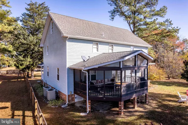 a patio with table and chairs and potted plants with wooden floor and fence