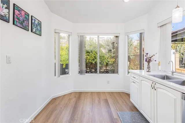 a view of a kitchen and an empty room with wooden floor and a window