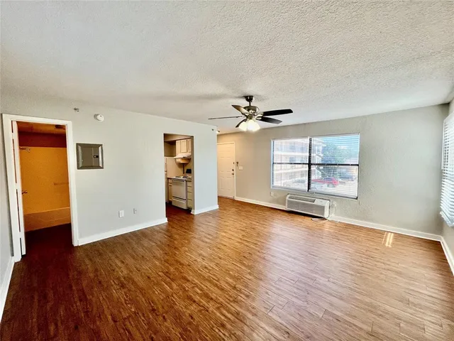 an empty room with wooden floor chandelier and windows