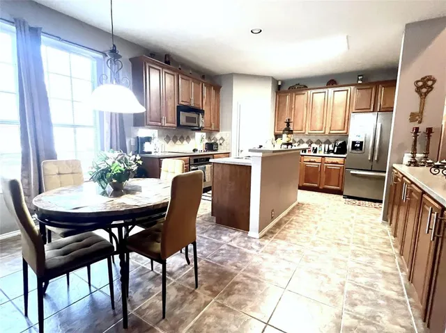 a kitchen with refrigerator a stove a dining table and chairs with wooden floor