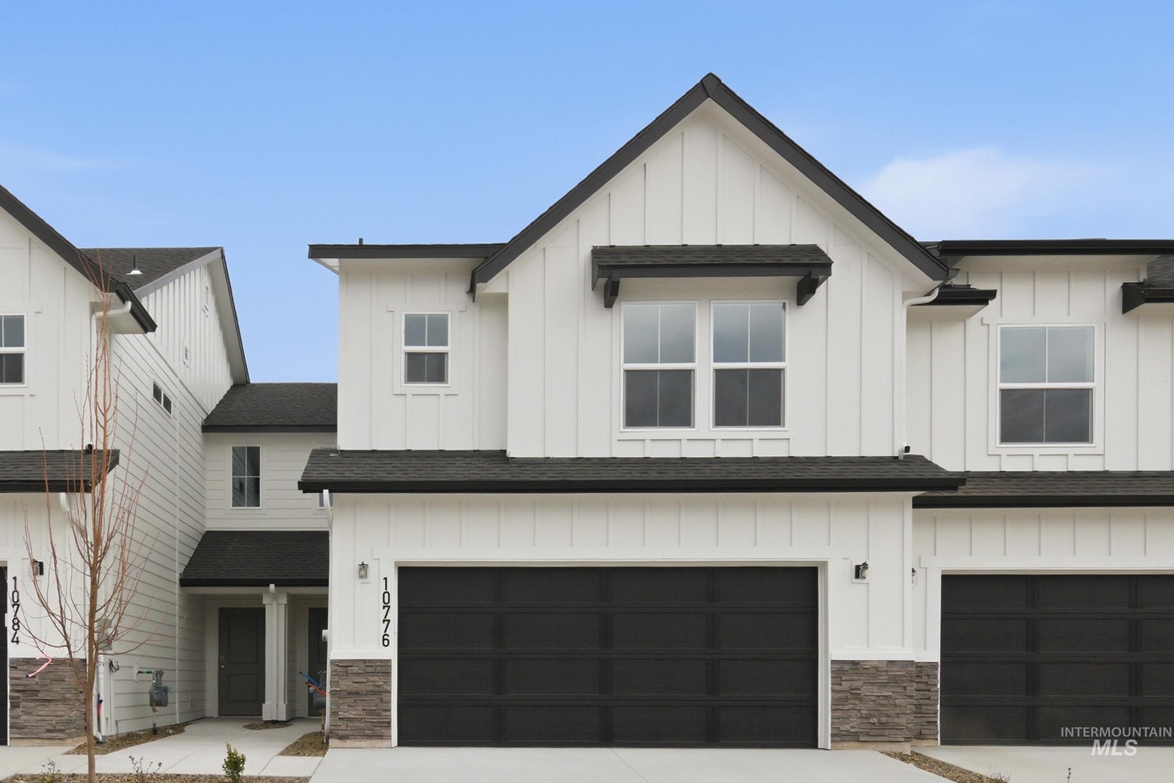 Modern farmhouse style home featuring board and batten siding, stone siding, and roof with shingles