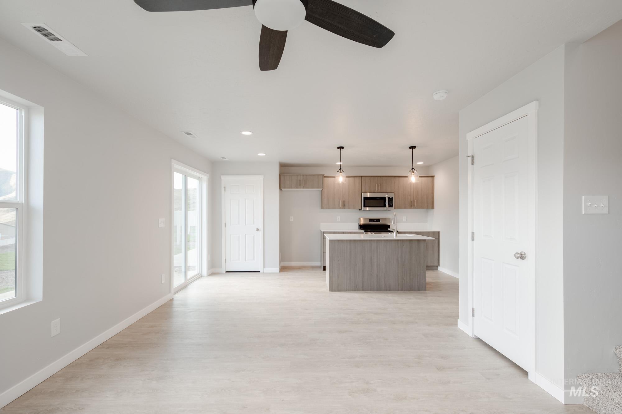 10776 Rutland Street Caldwell, ID 83605 - Photo 21 of 22 Kitchen featuring a center island with sink, light countertops, ceiling fan, open floor plan, and pendant lighting
