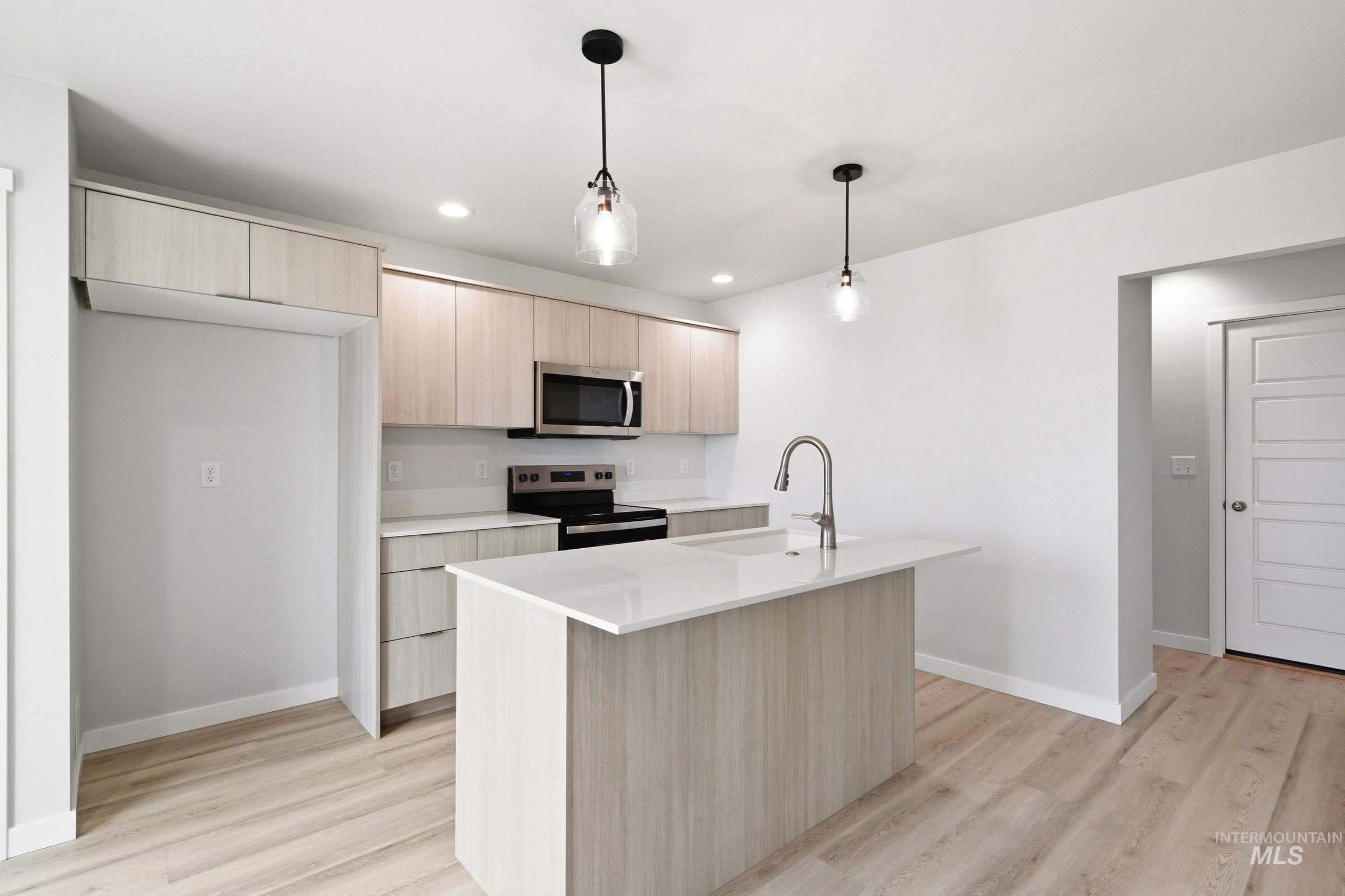 10776 Rutland Street Caldwell, ID 83605 - Photo 3 of 22 Kitchen with light wood finish cabinets, pendant lighting, modern cabinets, stainless steel appliances, and a center island with sink