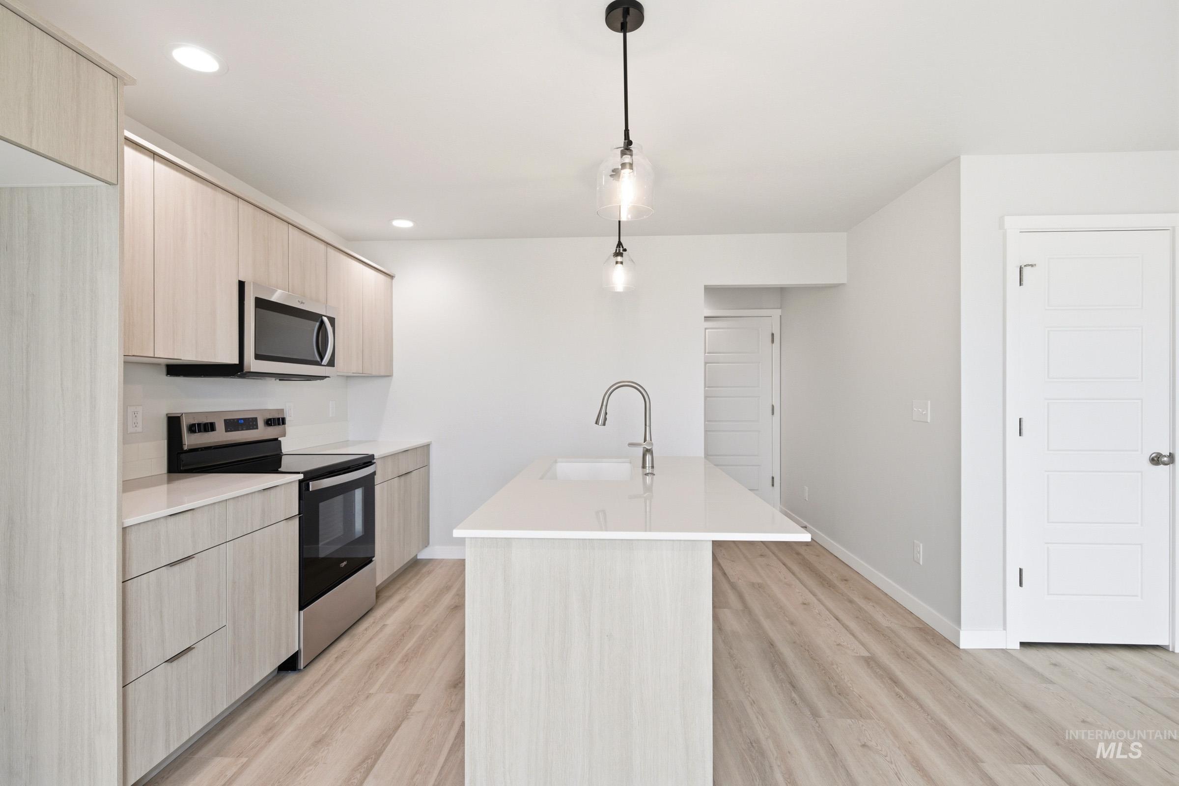 10776 Rutland Street Caldwell, ID 83605 - Photo 4 of 22 Kitchen featuring light wood finish cabinets, a center island with sink, stainless steel appliances, and light wood-style floors