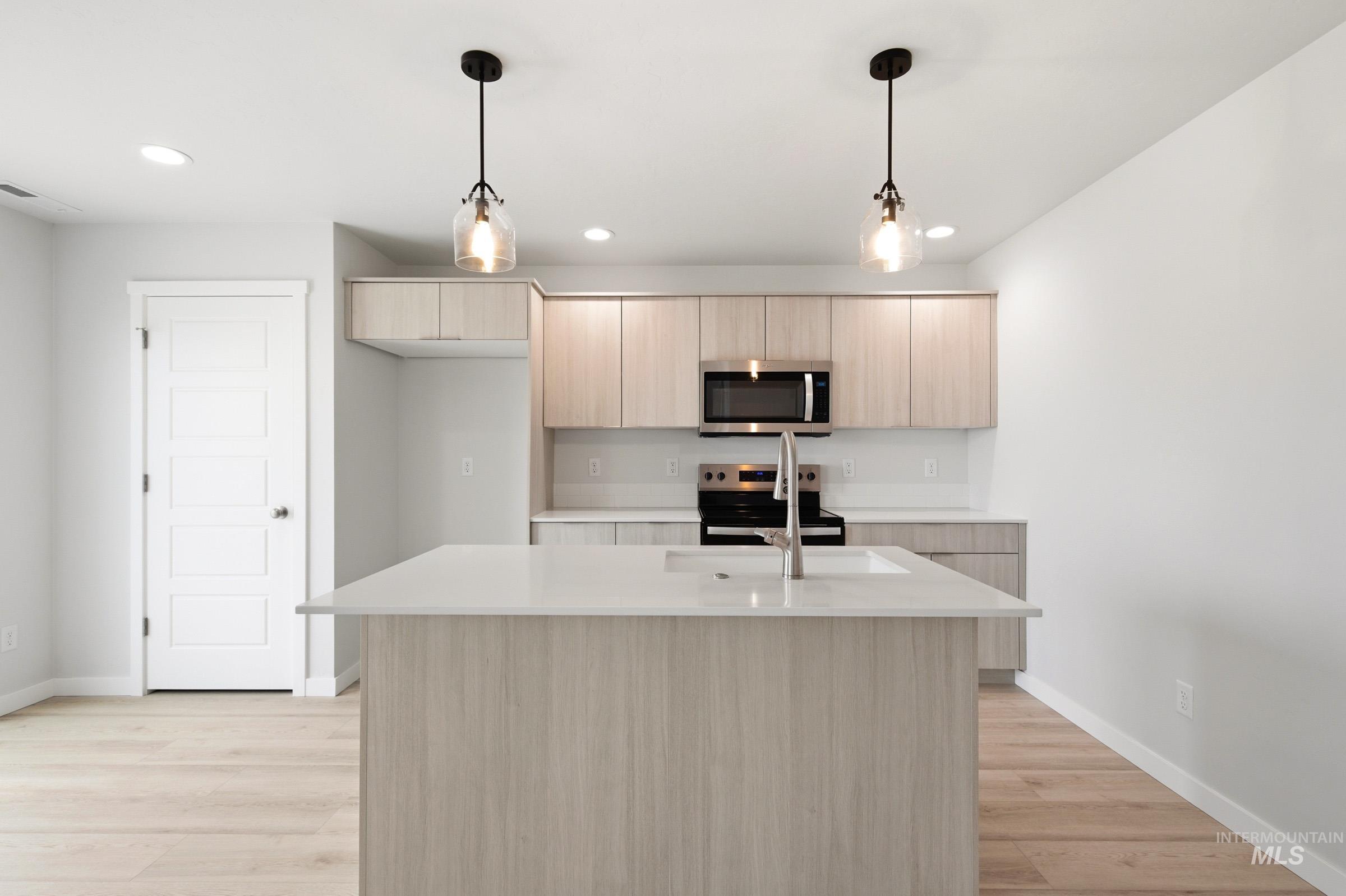 10776 Rutland Street Caldwell, ID 83605 - Photo 5 of 22 Kitchen with light wood finish cabinetry, modern cabinets, hanging light fixtures, and a kitchen island with sink