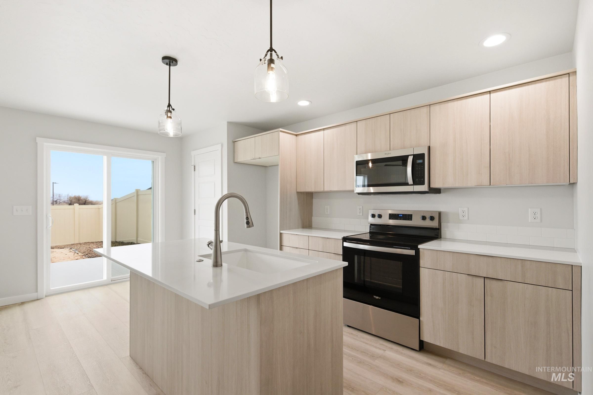 10776 Rutland Street Caldwell, ID 83605 - Photo 6 of 22 Kitchen with stainless steel appliances, light wood finish cabinetry, an island with sink, pendant lighting, and light wood-style flooring