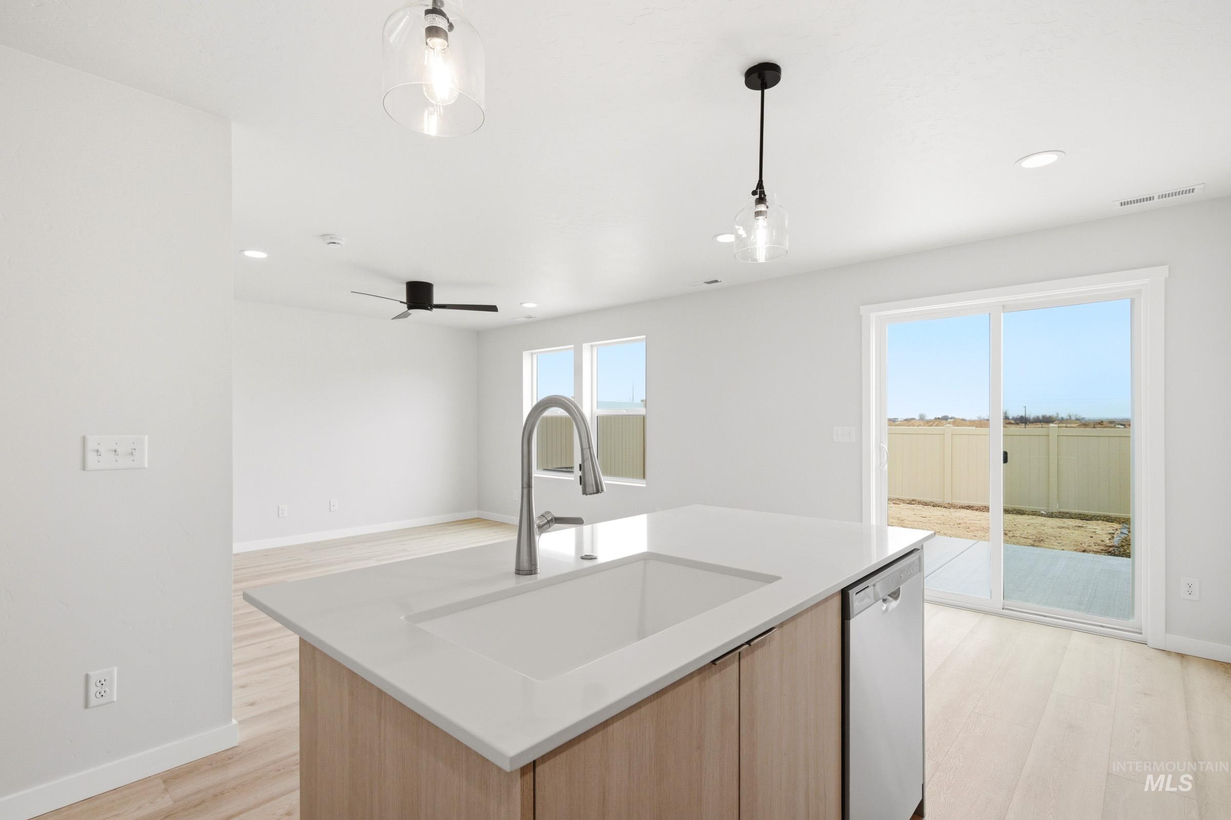 10776 Rutland Street Caldwell, ID 83605 - Photo 8 of 22 Kitchen with light wood-style flooring, an island with sink, dishwasher, pendant lighting, and light stone counters