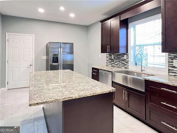 a kitchen with stainless steel appliances kitchen island granite countertop wooden cabinets sink and window