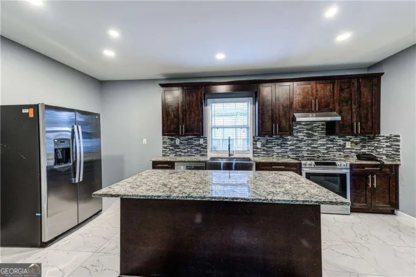 a kitchen with stainless steel appliances granite countertop a sink stove and refrigerator