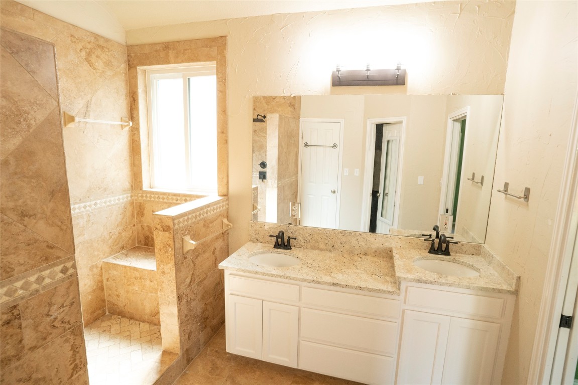 1712 Hackney Cove Austin, TX 78727 - Photo 20 of 38 a bathroom with a granite countertop sink a mirror and a shower