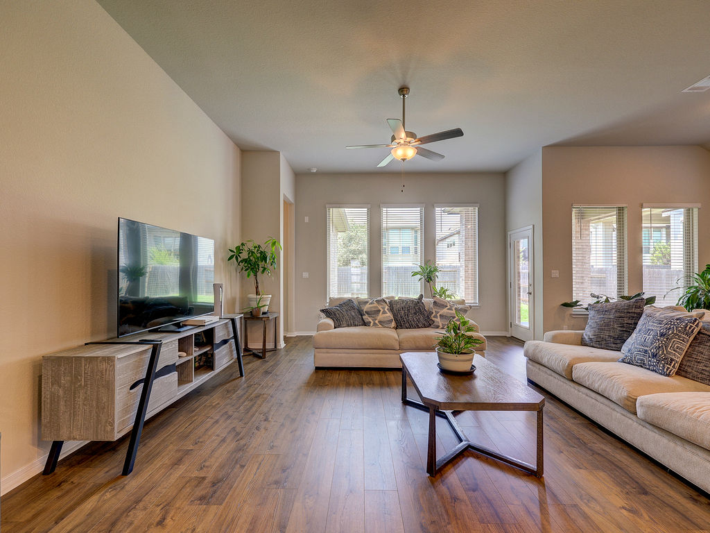 229 Heartleaf Road San Marcos, TX 78666 - Photo 19 of 40 Natural light pours into this spacious gathering area featuring warm wood flooring and direct outdoor access.