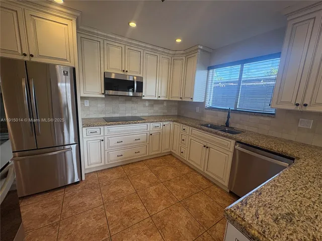 a kitchen with stainless steel appliances granite countertop a refrigerator and a sink