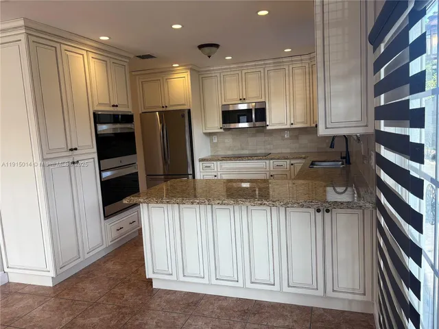 a kitchen with stainless steel appliances granite countertop a refrigerator and a sink