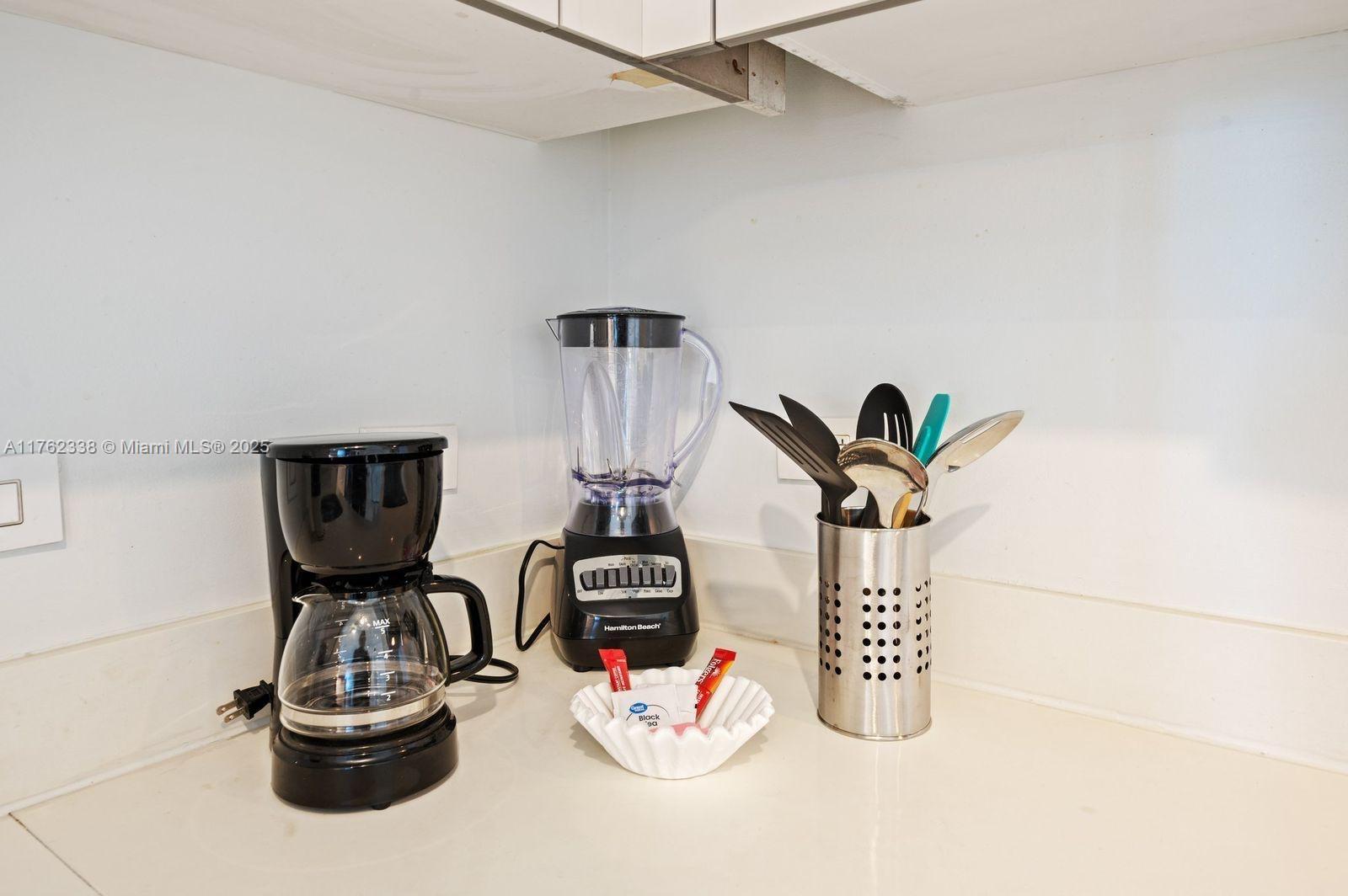 2602 East Hallandale Beach Boulevard, Unit R2703 Hallandale Beach, FL 33009 - Photo 19 of 50 a table with a vase and white cabinets