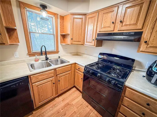 a kitchen with granite countertop a stove a sink and wooden cabinets