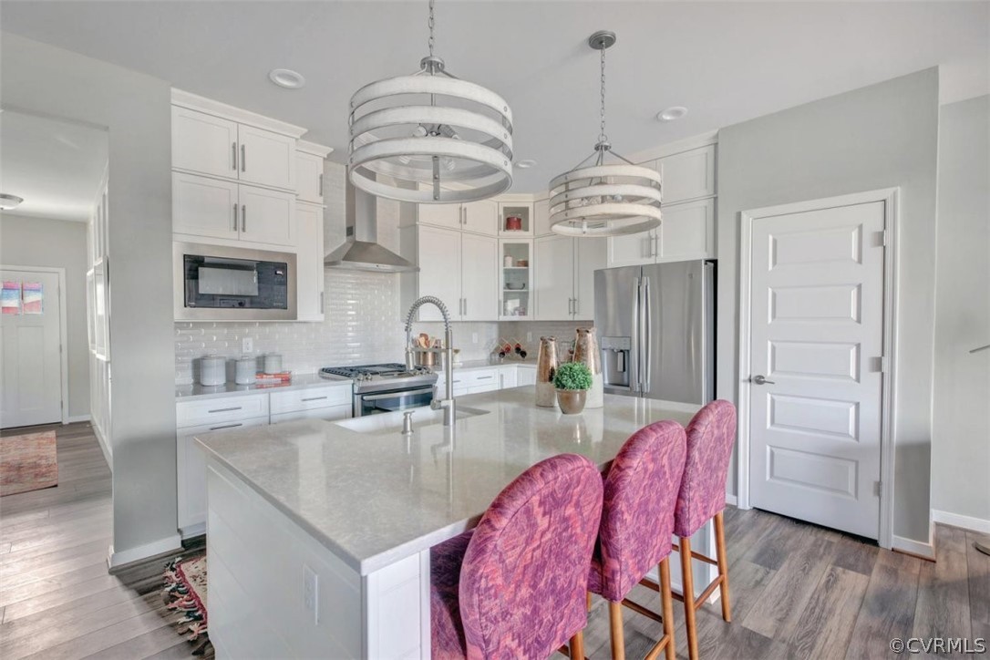 a kitchen with stainless steel appliances granite countertop a kitchen island a stove a sink dishwasher a dining table and chairs with wooden floor
