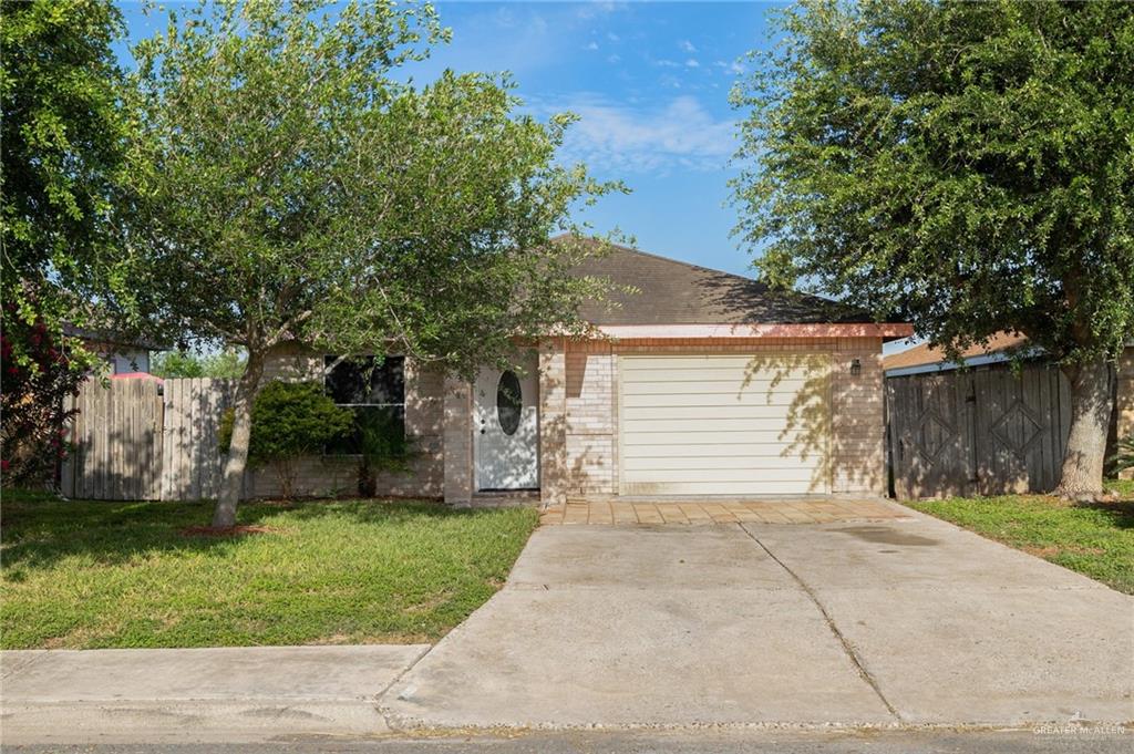 View of front of property with fence, a front lawn, brick siding, and a garage