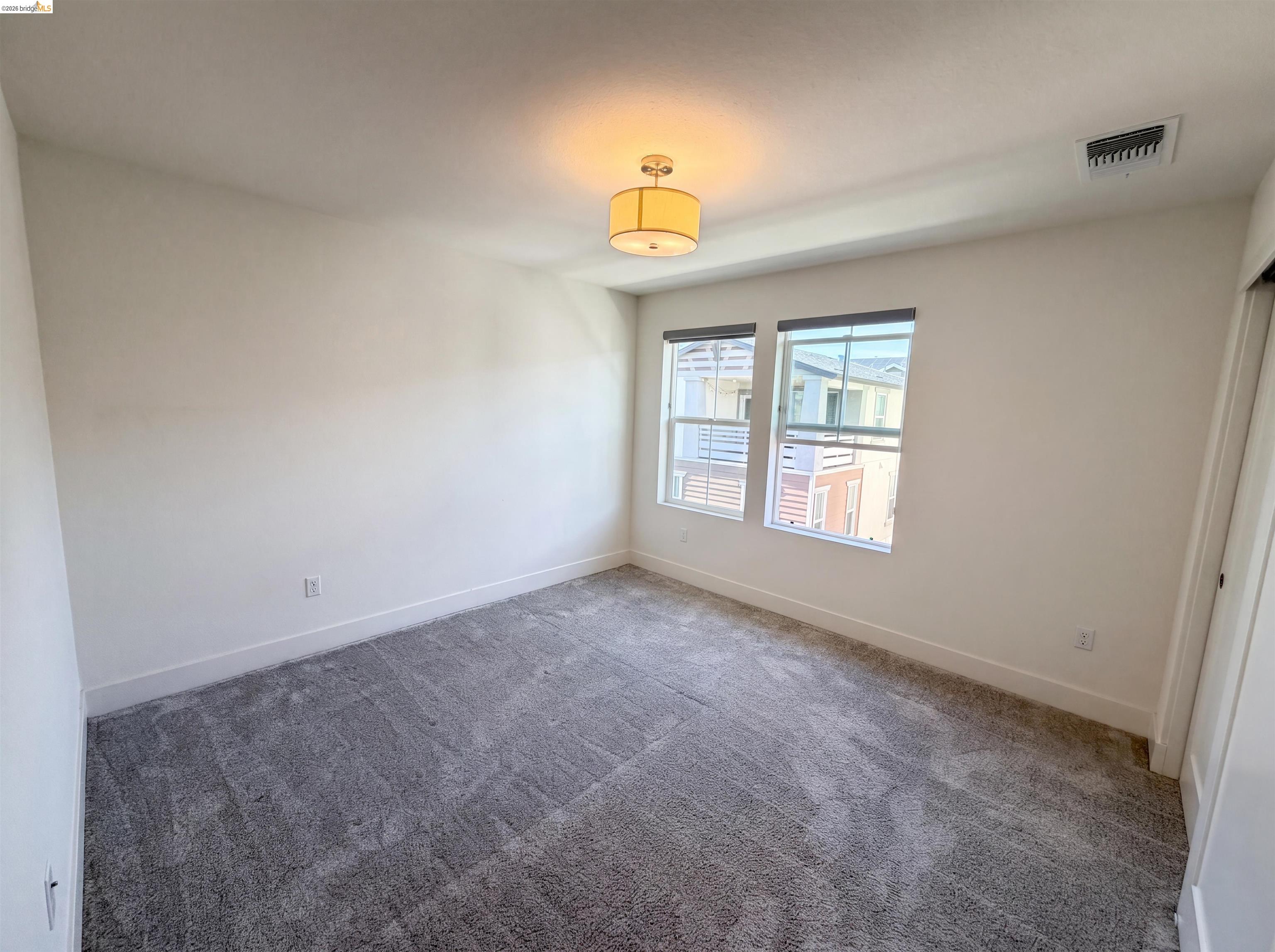 9034 Rudder Way Newark, CA 94560 - Photo 9 of 38 Bright room featuring two large windows, gray patterned carpeting, white baseboards, and a drum-style ceiling light fixture