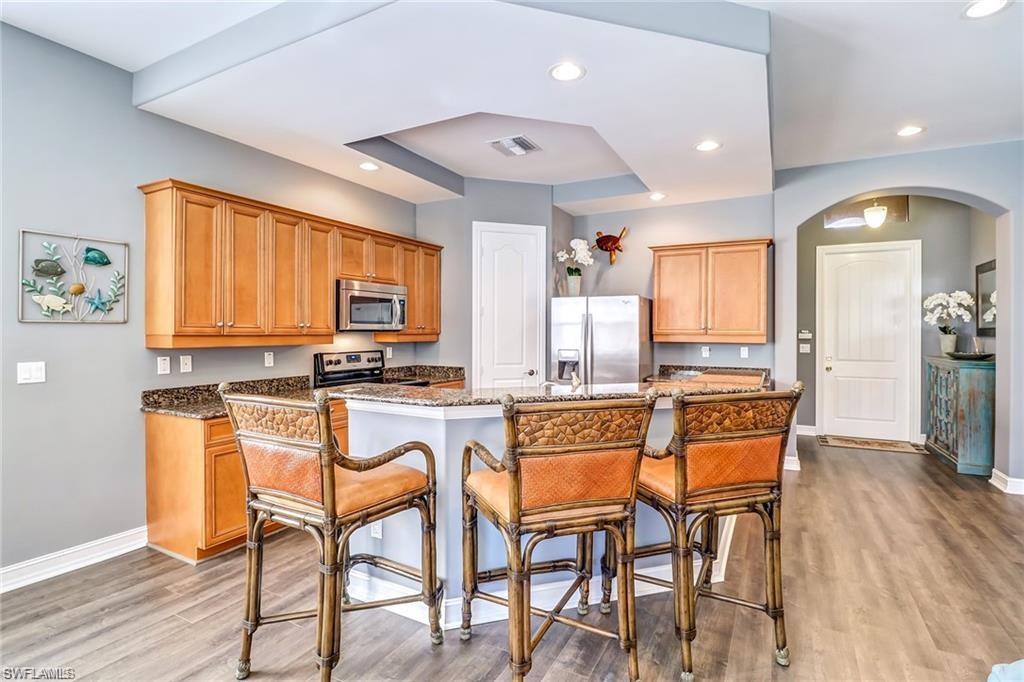 1374 Serrano Circle Naples, FL 34105 - Photo 11 of 37 a kitchen with stainless steel appliances granite countertop dining table chairs refrigerator and sink