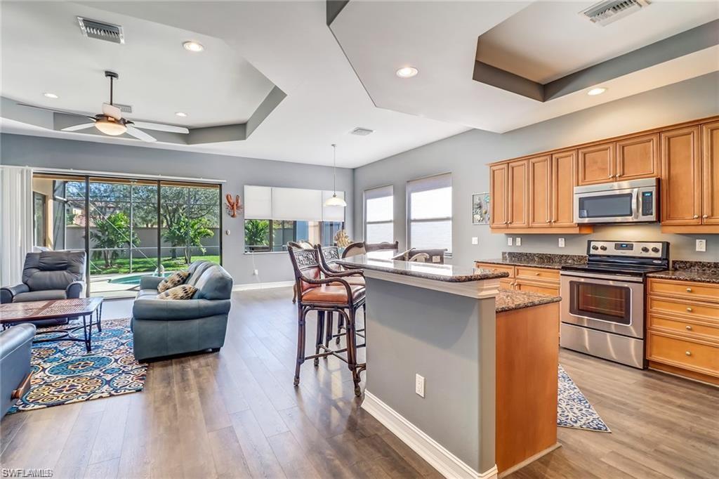 1374 Serrano Circle Naples, FL 34105 - Photo 10 of 37 a kitchen with stainless steel appliances granite countertop a stove top oven a sink dishwasher a dining table and chairs with wooden floor